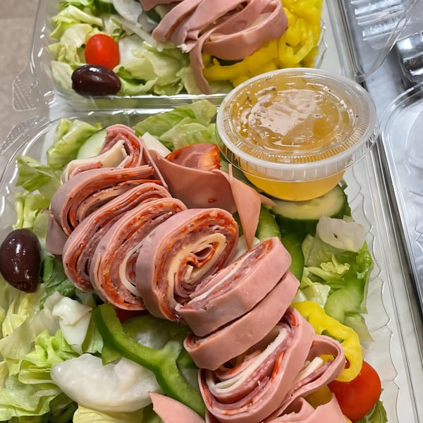 Two South St Pizzeria salads with rolled deli meats, lettuce, olives, tomatoes, and dressing.
