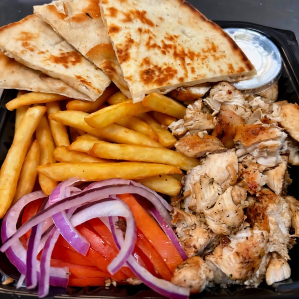 A South St Pizzeria chicken gyro platter with pita, fries, sliced onions, tomatoes, and sauce.